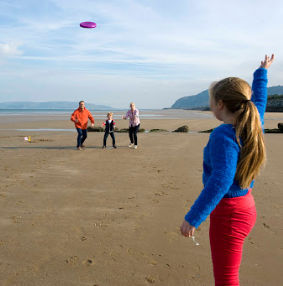 Teulu yn chwarae ffrisbi ym Mhenmaenmawr